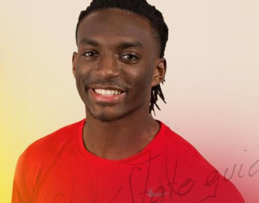 Smiling man wearing a red shirt, with short dreadlocks. The background is softly blurred in shades of light beige and yellow, conveying a cheerful tone.