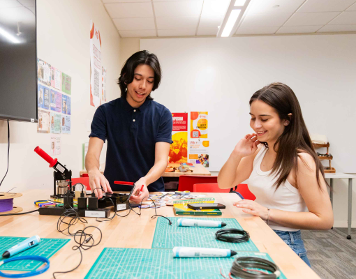 Two Stanislaus State students work together with electronics and tools at a table in a campus lab.
