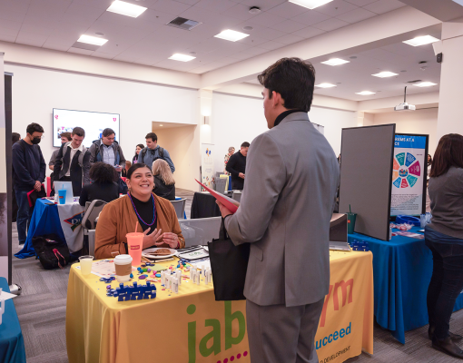 Employers at tables talking with students in professional attire