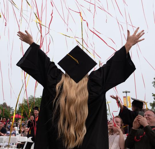 College graduate spreading their arms with a cap and gown on