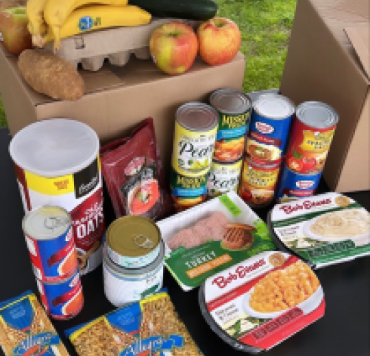 Imagen de alimentos en una caja de cartón y exhibidos sobre una mesa.