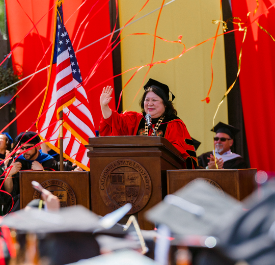 President Junn at podium in regalia during her final Commencement ceremony.