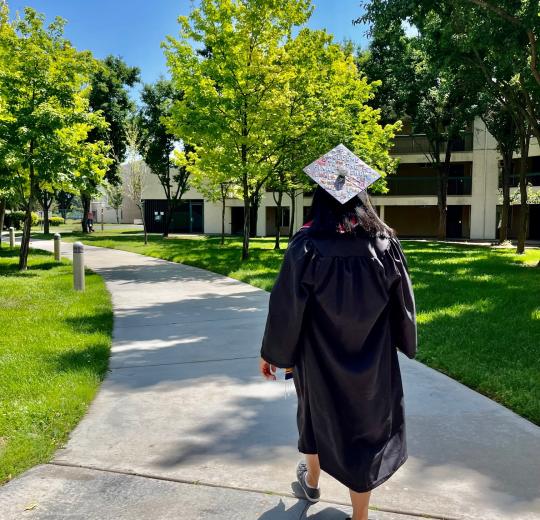 student walking in grad gown through village 2