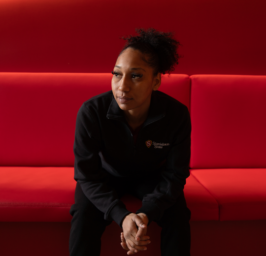 stan state student sitting on red couch looking off-screen to left 