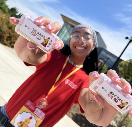 Student holding mint boxes that read make us your first pick