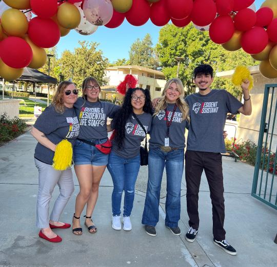 housing staff standing under balloon arch