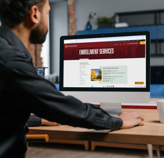 A student views the Stan State Enrollment Services website on a desktop.