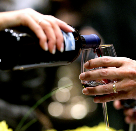 An individual pouring wine into a wine glass.