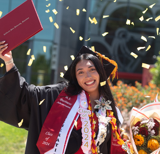 Graduate posing for photo in the Quad area.