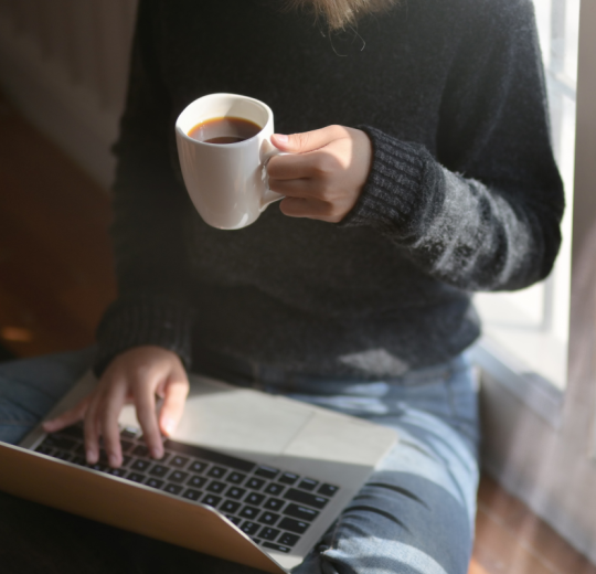 Person on a computer holding coffee mug