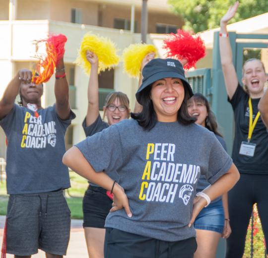 peer academic coach standing in front of students waving pom poms