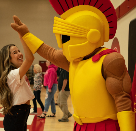Student smiling and giving Titus a high five