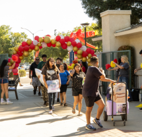 Students with luggage are seen walking through the Housing Residential Village at Stan State during move-in day