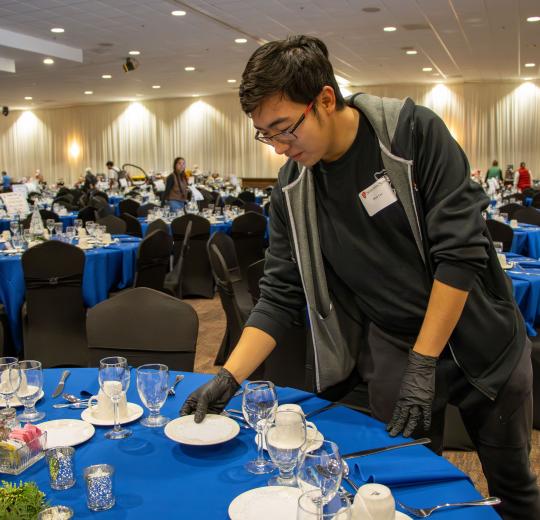 Student volunteer Dean Lee sets a table at Legacy of Hope.