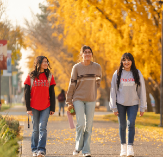 Three students walking on the campus grounds at Stan State