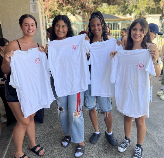 4 female students stand displaying housing shirts