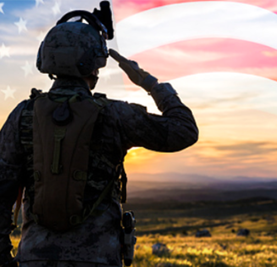 Veteran observing the sunset with an American flag in the background.