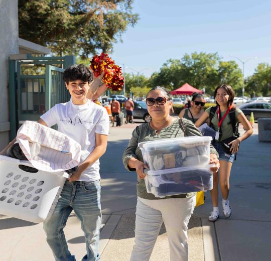 two students carry moving boxes through a set of gates