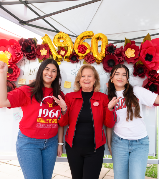 President Britt Rios-Ellis with students in front of the donor thank you board.