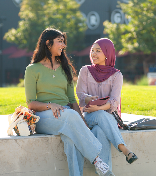 Two students sitting outdoors. 