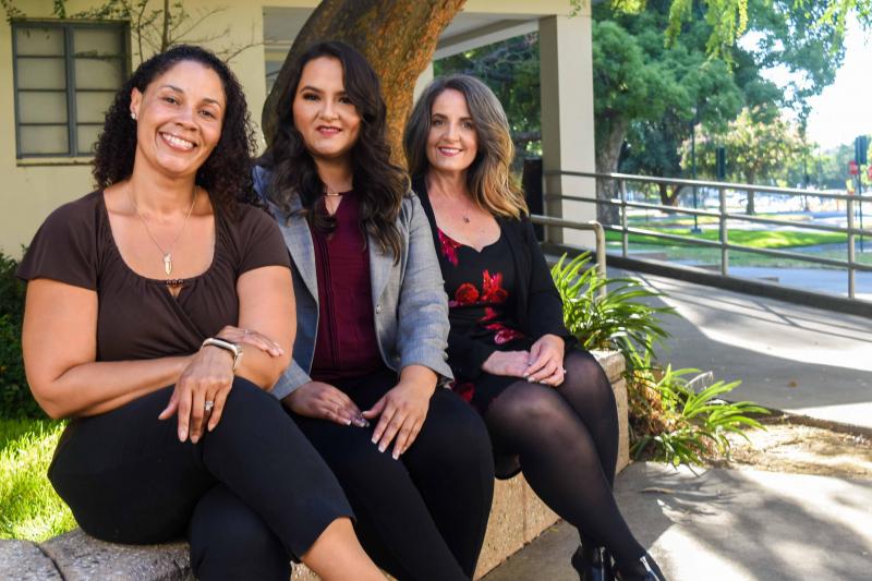 Three women who graduated from the accelerated bachelor's degree program sit outside at the Stan State Stockton Center campus.