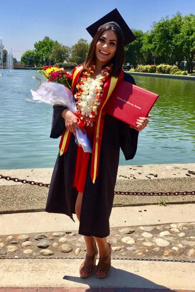 Cody Yamada poses in her graduation gown at the University reflecting pond.