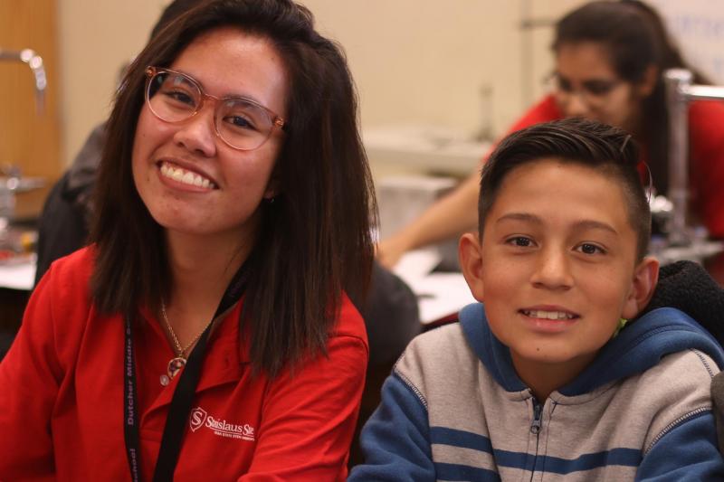 Stan State student Serene Aman smiles beside 7th-grader Miael Guevara in the Dutcher lab